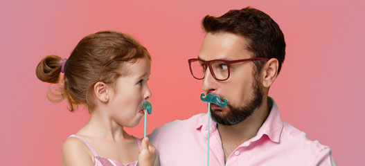 padre e hija poniendo caras con bigote de cartón
