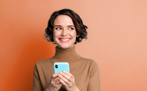 chica con un móvil en la mano poniendo cara de pilla