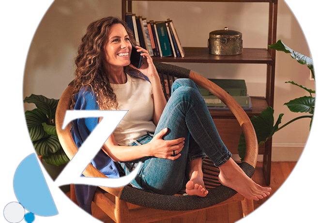 chica sonriendo, entada de forma relajada en una silla, hablando por teléfono