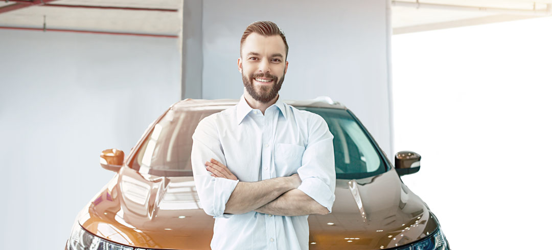 Hombre sonriendo con su coche detrás