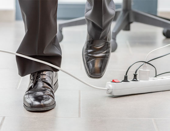 Persona andando y cruzándose con un cable de una regleta